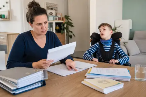 „Pflegebegutachtung bei Kindern – Fristen“: Eltern und eine Fachberaterin besprechen zu Hause die Unterstützung eines pflegebedürftigen Kindes.