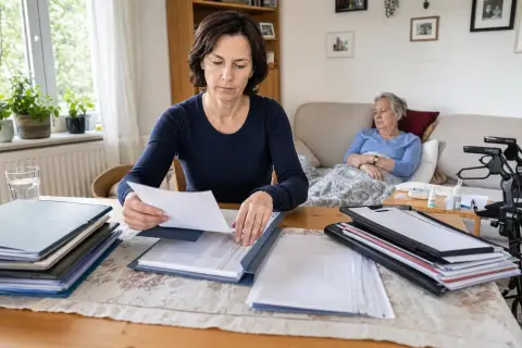 „Kurzzeitige Arbeitsverhinderung – Unterlagen“: Eine pflegende Angehörige prüft Unterlagen zur Vereinbarkeit von Beruf, Absicherung und Pflege.