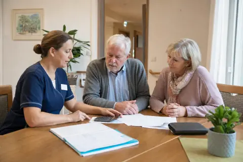 Kurzzeitpflege – Kosten „Kurzzeitpflege – Kosten“: Eine Pflegefachperson bespricht mit einer pflegebedürftigen Person die weitere Versorgung nach einer Behandlung.