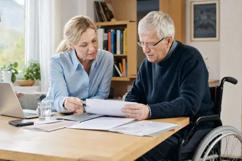 „Pflegegeld – Antrag“: Eine Angehörige und eine pflegebedürftige Person prüfen gemeinsam Pflegeunterlagen an einem Tisch.