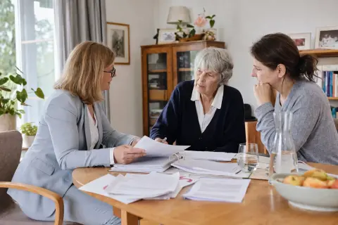 Pflegegrad erhöhen: Wann ein Höherstufungsantrag sinnvoll ist „Pflegegrad erhöhen: Wann ein Höherstufungsantrag sinnvoll ist“: Eine Angehörige und eine pflegebedürftige Person prüfen gemeinsam Pflegeunterlagen an einem Tisch.