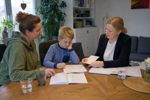 „Pflegegrad für ein Kind – Fristen“: Eltern und eine Fachberaterin besprechen zu Hause die Unterstützung eines pflegebedürftigen Kindes.