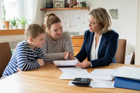 „Pflegegrad für ein Kind – Kosten“: Eltern und eine Fachberaterin besprechen zu Hause die Unterstützung eines pflegebedürftigen Kindes.
